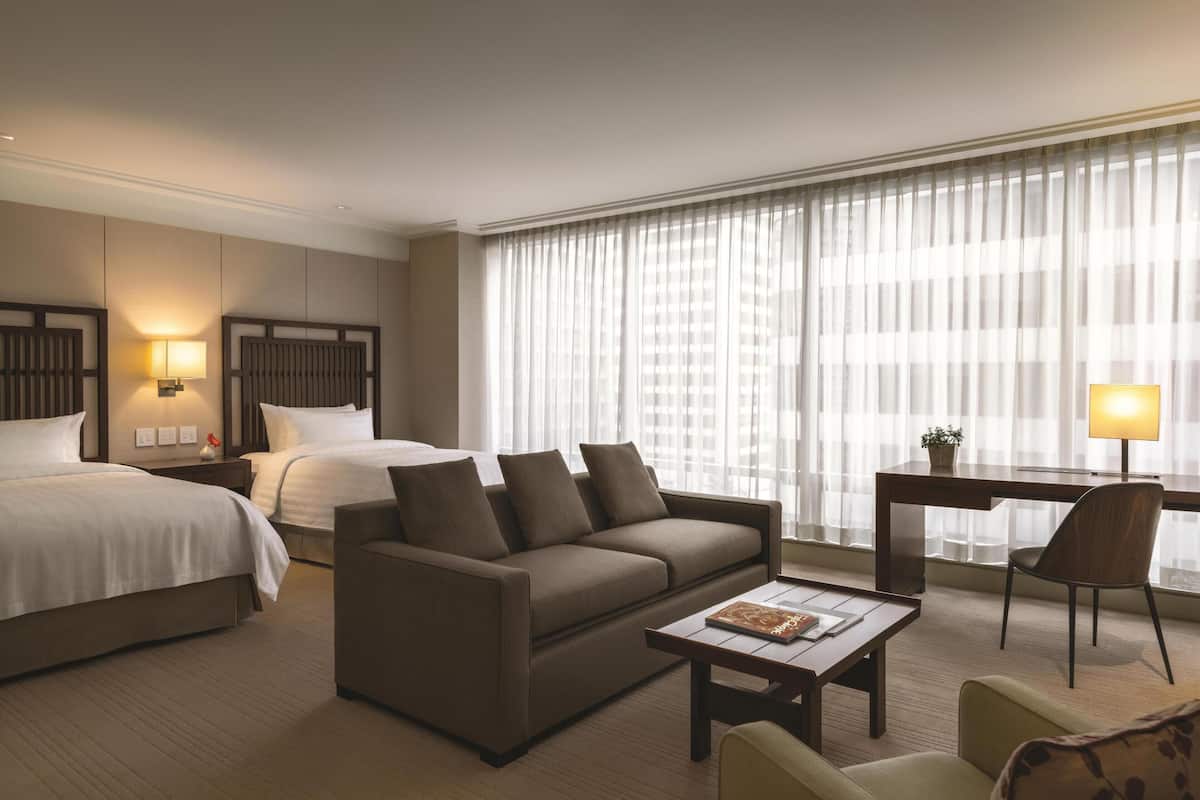 Une chambre d’hôtel avec un lit, un canapé, un bureau et une chaise.
