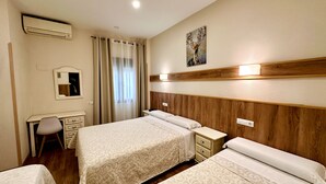 A hotel room with a large bed, a desk, a chair, a mirror, and a painting on the wall. - Hostal Toledo (Toledo)