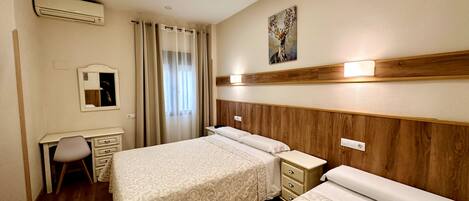 A hotel room with a large bed, a desk, a chair, a mirror, and a painting on the wall.