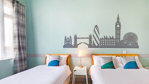 A hotel room with two beds, a nightstand with a lamp, and a wall mural of London landmarks. - OYO The Green Man Pub and Hotel (Wembley)