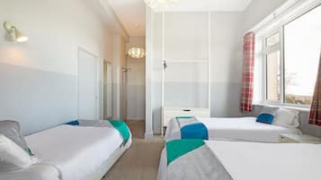 A hotel room with two single beds, a desk, a wardrobe, and a shower area.