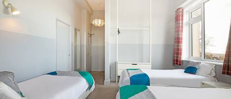Une chambre d’hôtel avec deux lits simples, un bureau, une armoire et un espace douche.
