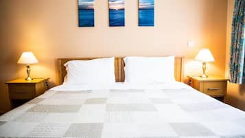 A hotel room with a bed, two bedside tables, and three wall-mounted paintings.