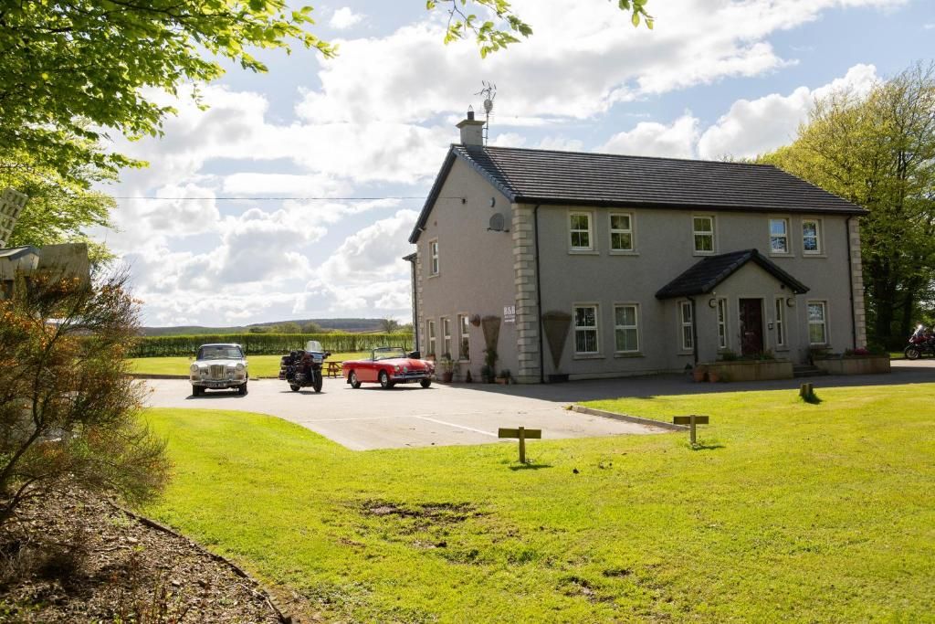 A two-story building with a flat roof and a chimney, located in a grassy area with a paved driveway.