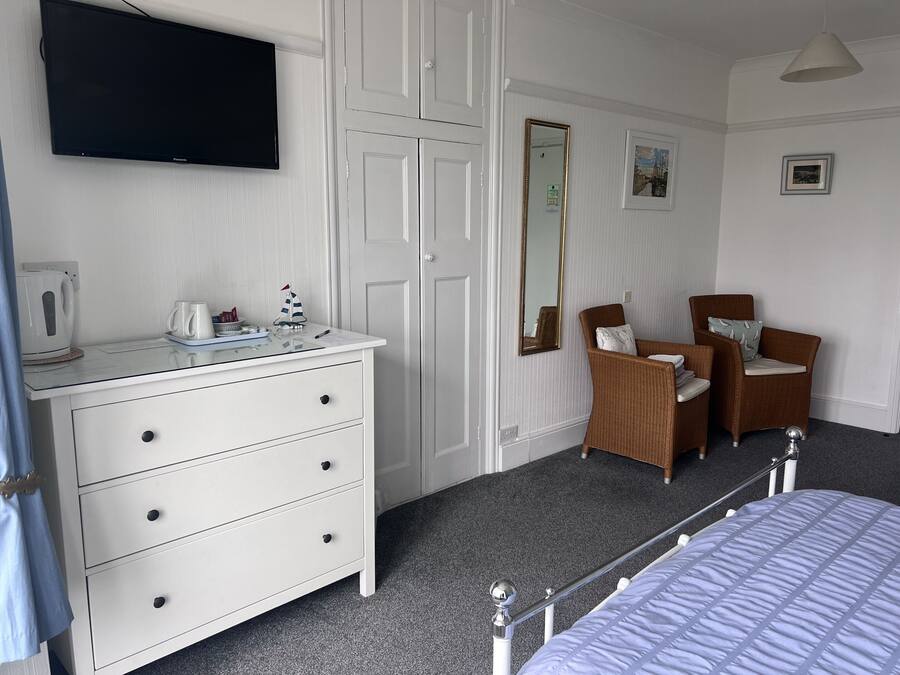 A bedroom with a bed, a dresser, a television, a chair, and a mirror.