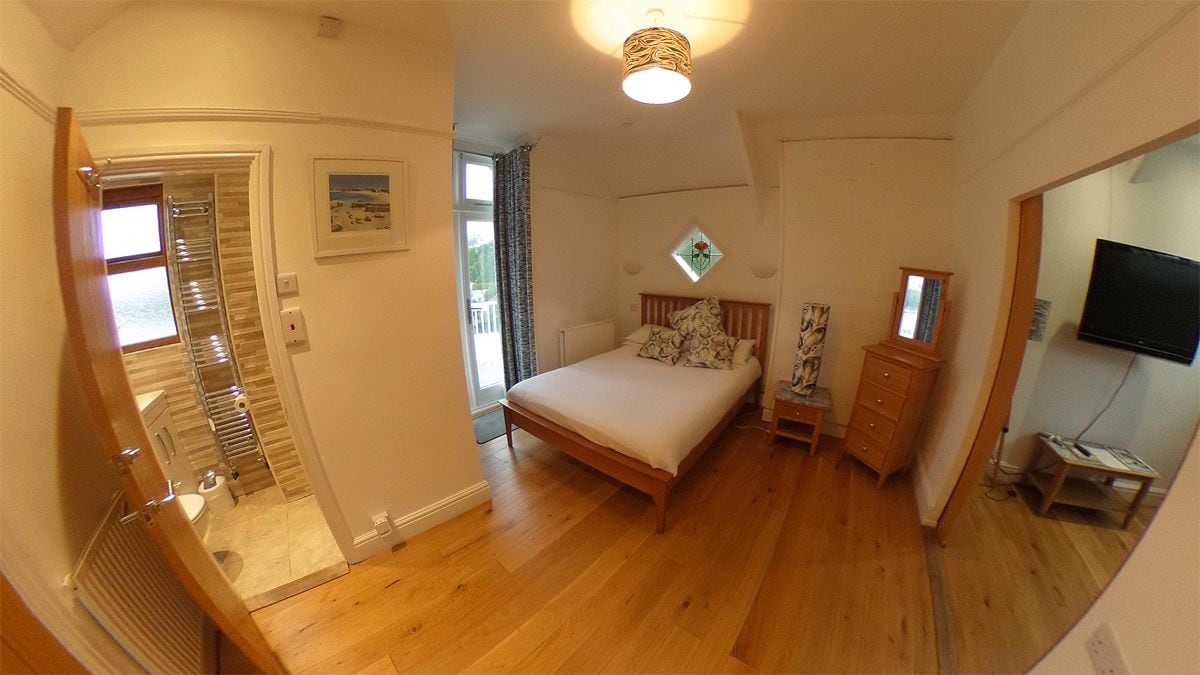 Ein Schlafzimmer mit einem Bett, einem Schminktisch, einem Fernseher und einem Fenster.