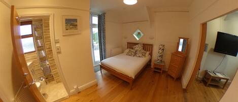 A bedroom with a bed, a dresser, a television, and a window.