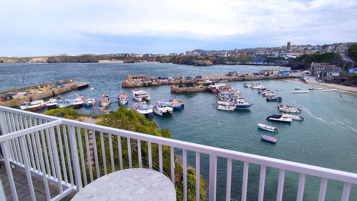 Un port avec des bateaux amarrés, une vue sur la ville en arrière-plan et un balcon avec une balustrade.