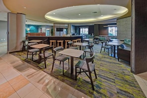 A hotel lobby with multiple seating areas, a reception desk, and a large window providing natural light. - Springhill Suites Naples (Naples)