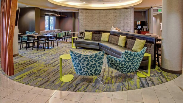 Un moderno vestíbulo de hotel con una zona de estar curva, un mostrador de recepción y un comedor.