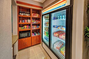 Una cuina americana amb microones, prateleires plenes d'aperitius i un frigorífic amb begudes i aliments.