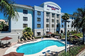 A hotel with a swimming pool, sun loungers, and palm trees. - Springhill Suites Naples (Naples)