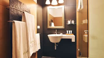 Un baño moderno con un espejo grande, un lavamanos y una cabina de ducha de vidrio.