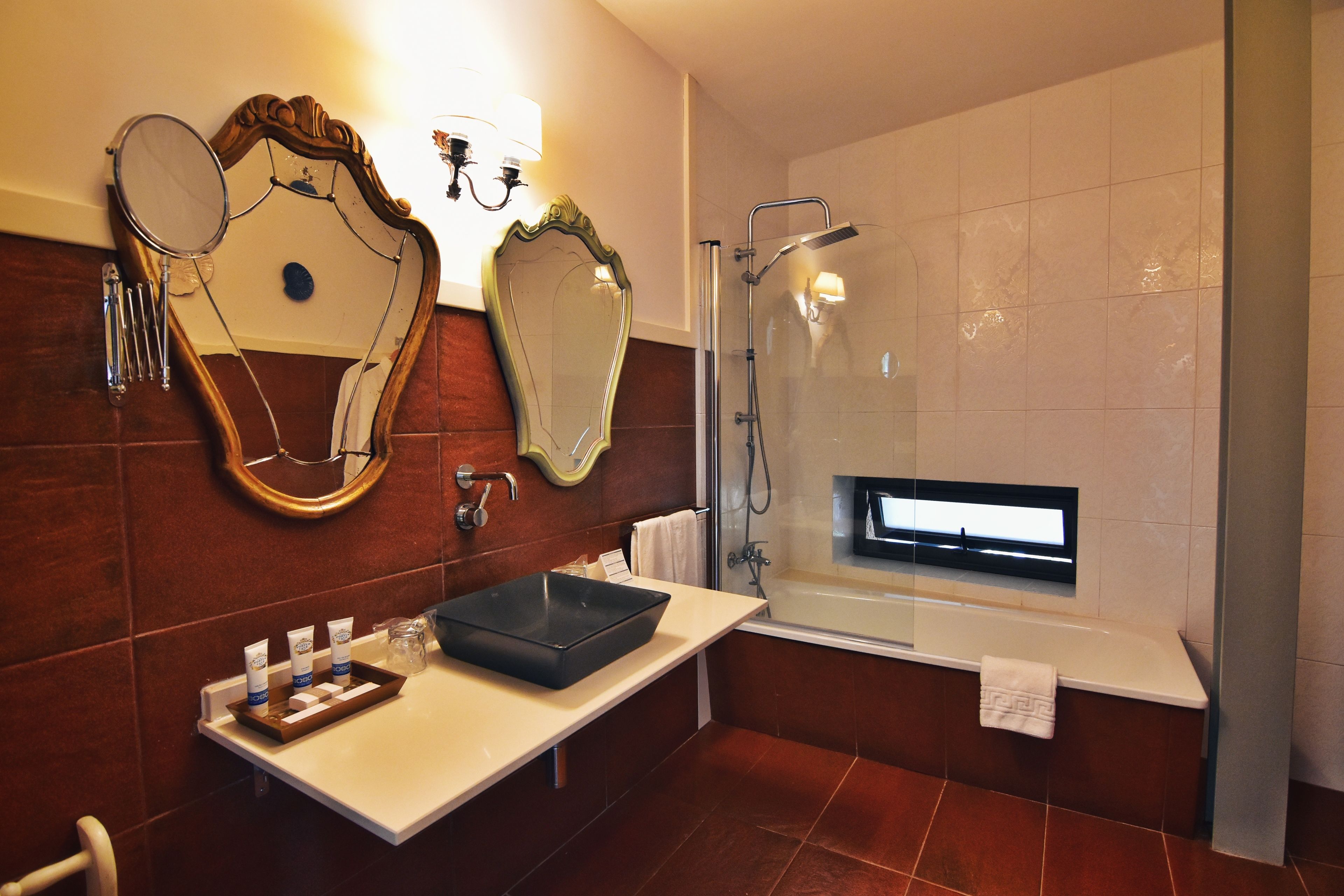 Ein modernes Badezimmer mit großem Spiegel, einer Badewanne und einem Waschtisch mit Pflegeprodukten.