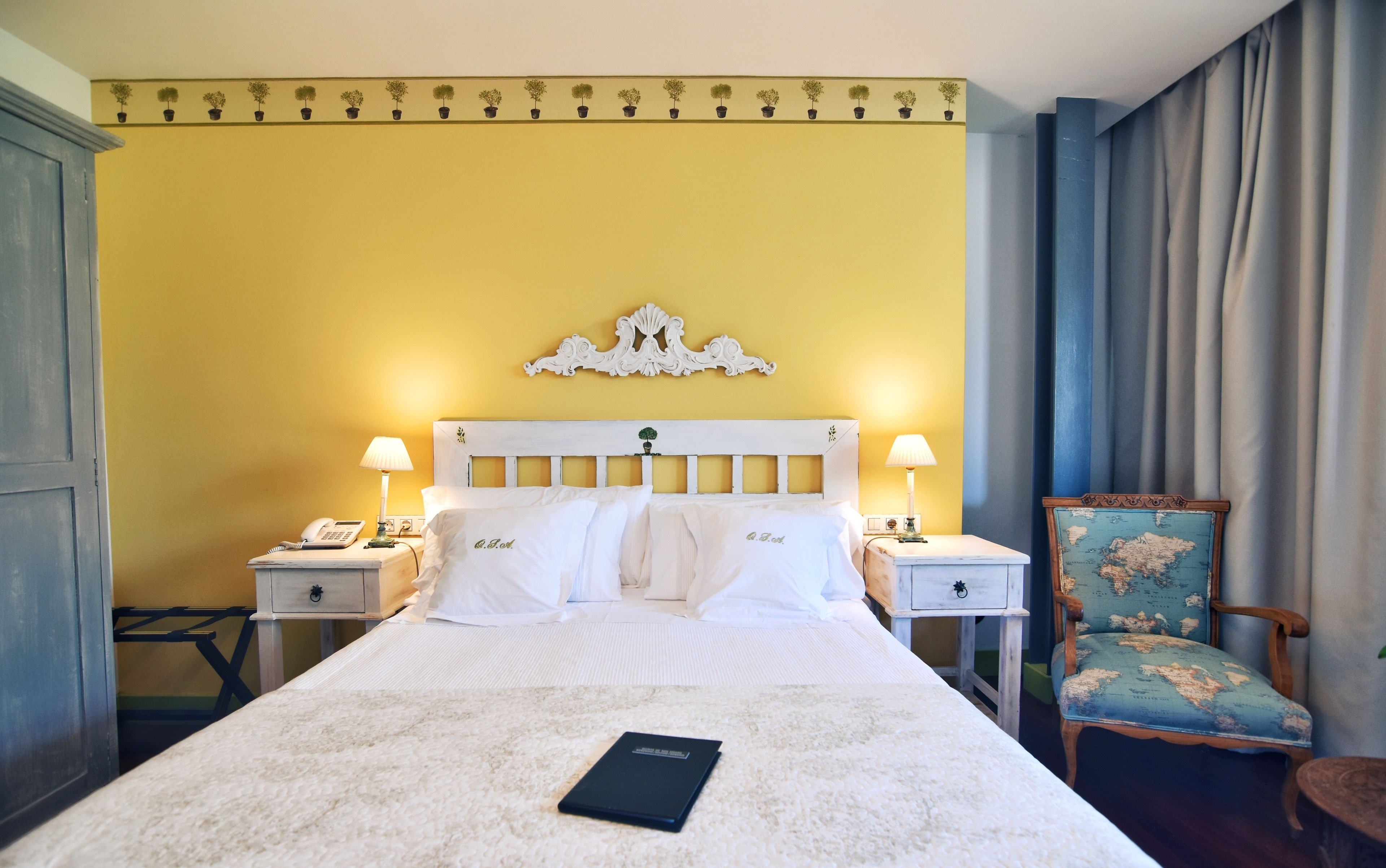 Una habitación de hotel con una cama, dos mesitas de noche, una silla y un mapa del mundo en la pared.