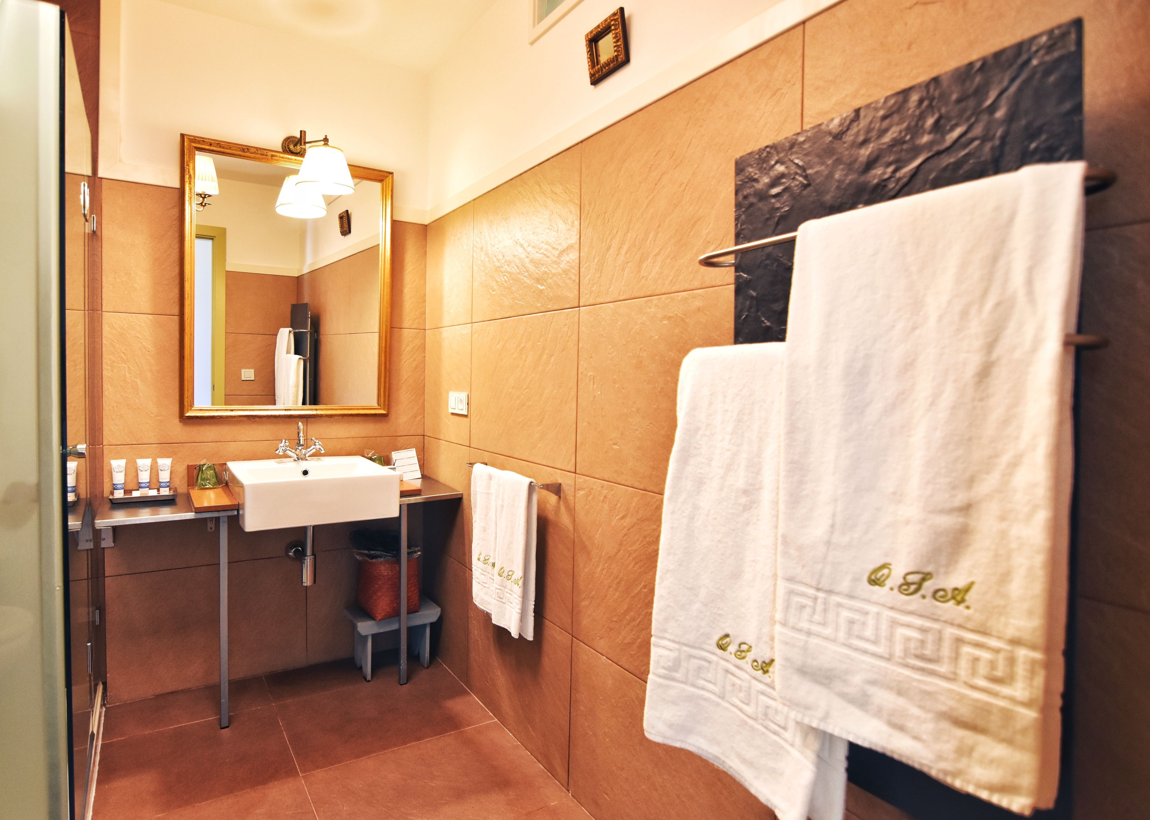 A bathroom with a sink, mirror, towel rack, and a decorative wall piece.