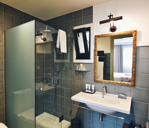 A modern bathroom with a glass-enclosed shower, a white sink, and a large mirror with a gold frame. - Quinta de San Amaro (Meano)
