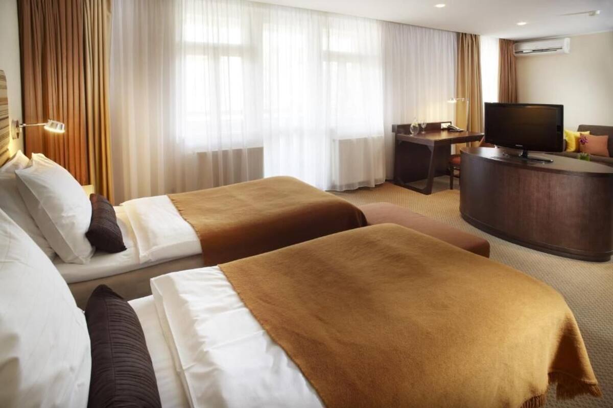 Una habitación de hotel con dos camas, un escritorio, un televisor y aire acondicionado.