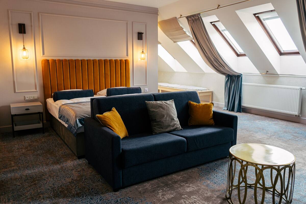 Habitación de hotel moderna con una cama grande, un sofá y una pequeña mesa. Cuenta con tragaluces y vistas al cielo.