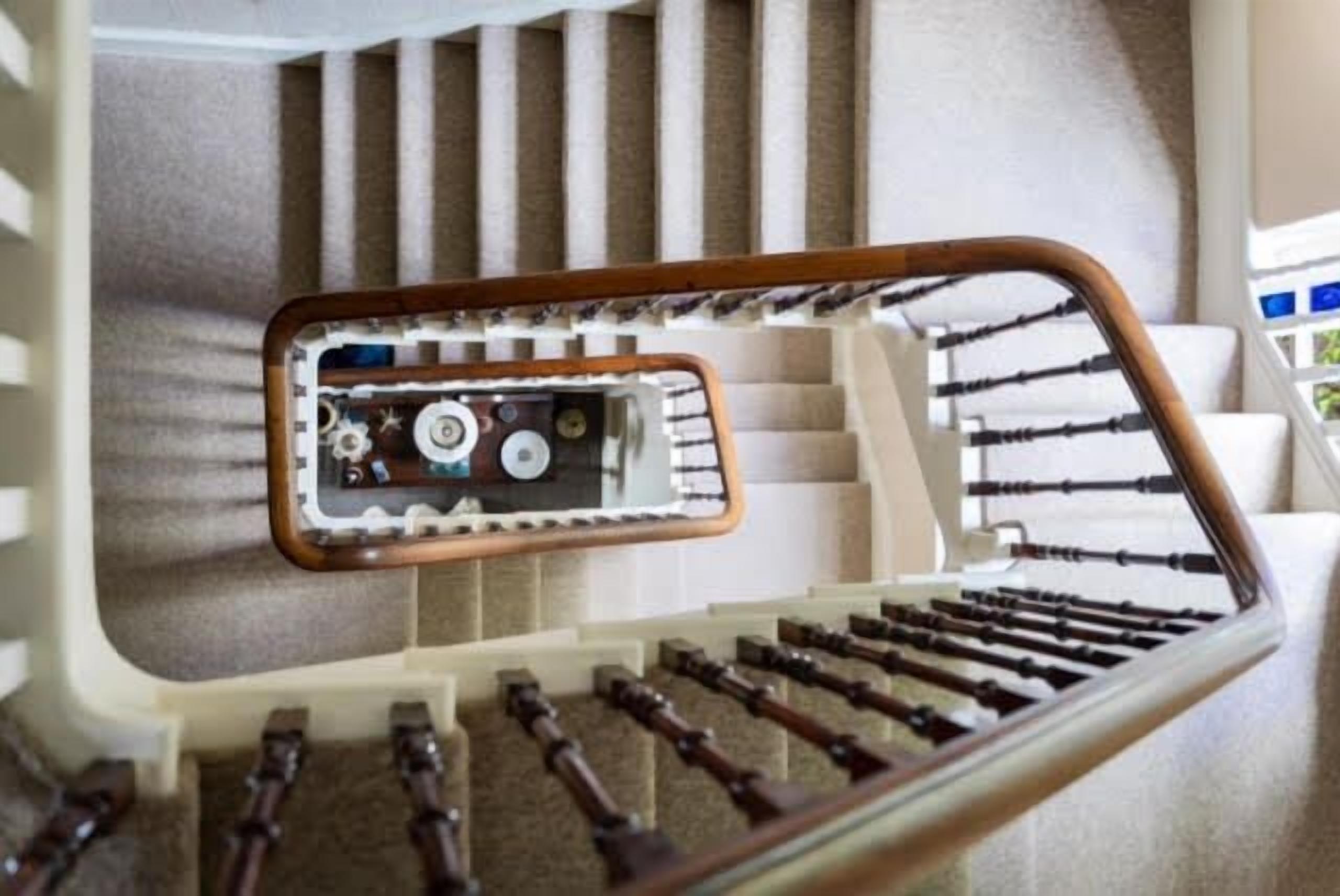 Una escalera con barandilla de madera y un panel de vidrio en la parte superior.