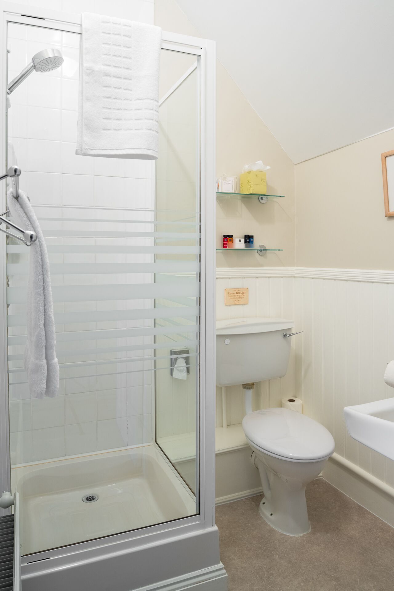 Un baño con ducha de vidrio, inodoro y lavamanos.