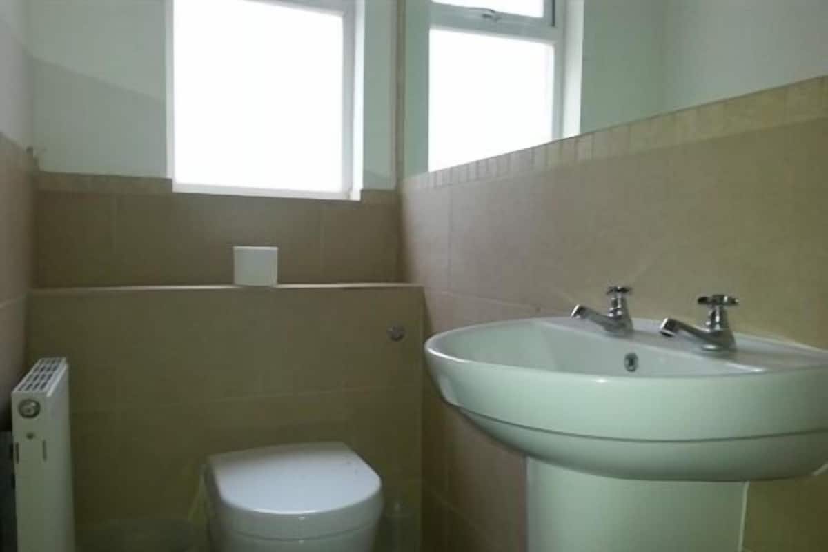 A small bathroom with a toilet, a sink, and a window above the sink.