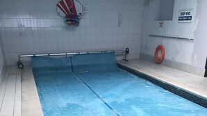 En swimmingpool med ett kaklat botten, en räddningsstång och en skylt som visar var det är djupt.