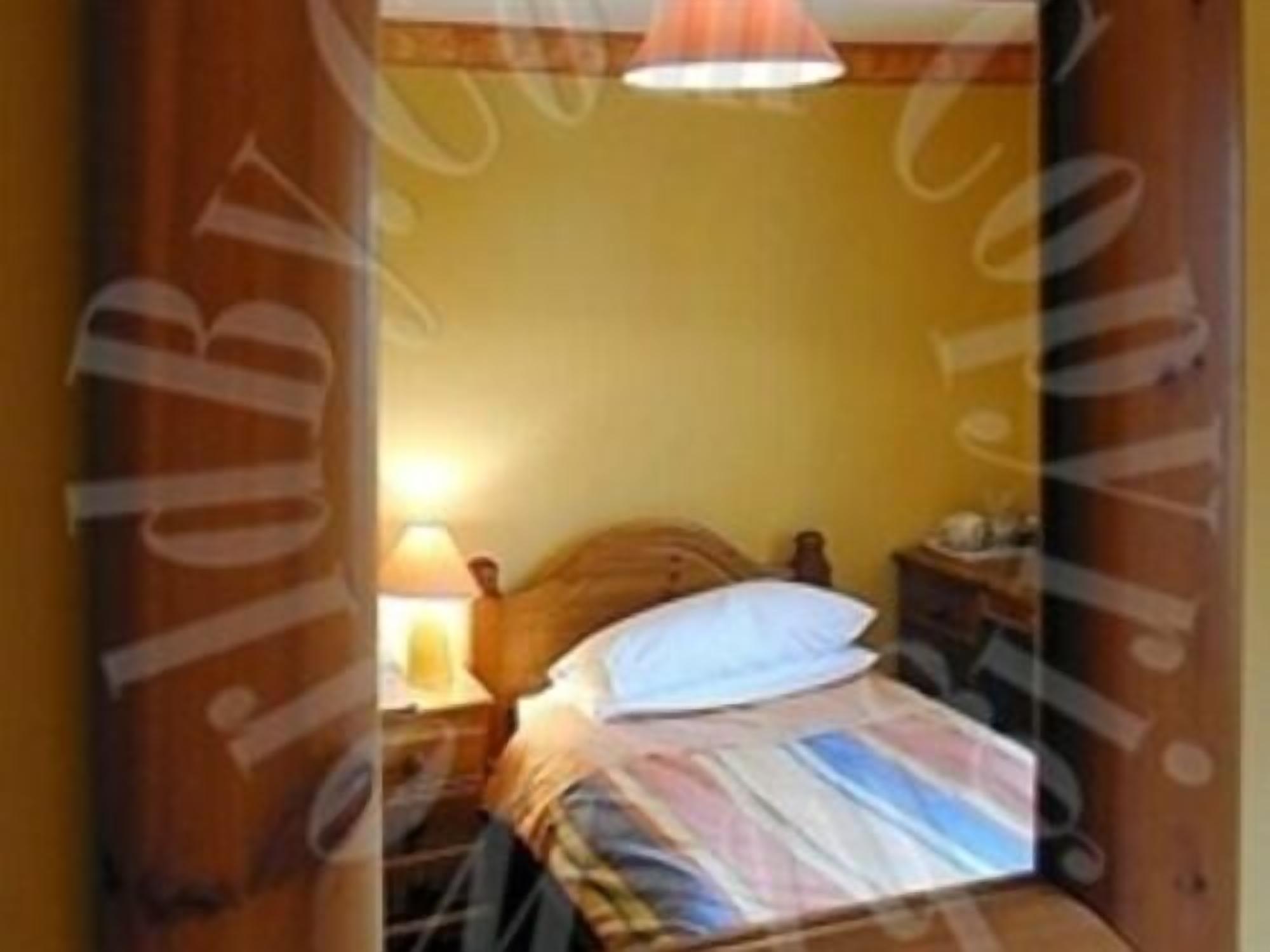 Una habitación pequeña con cama, mesita de noche y lámpara.