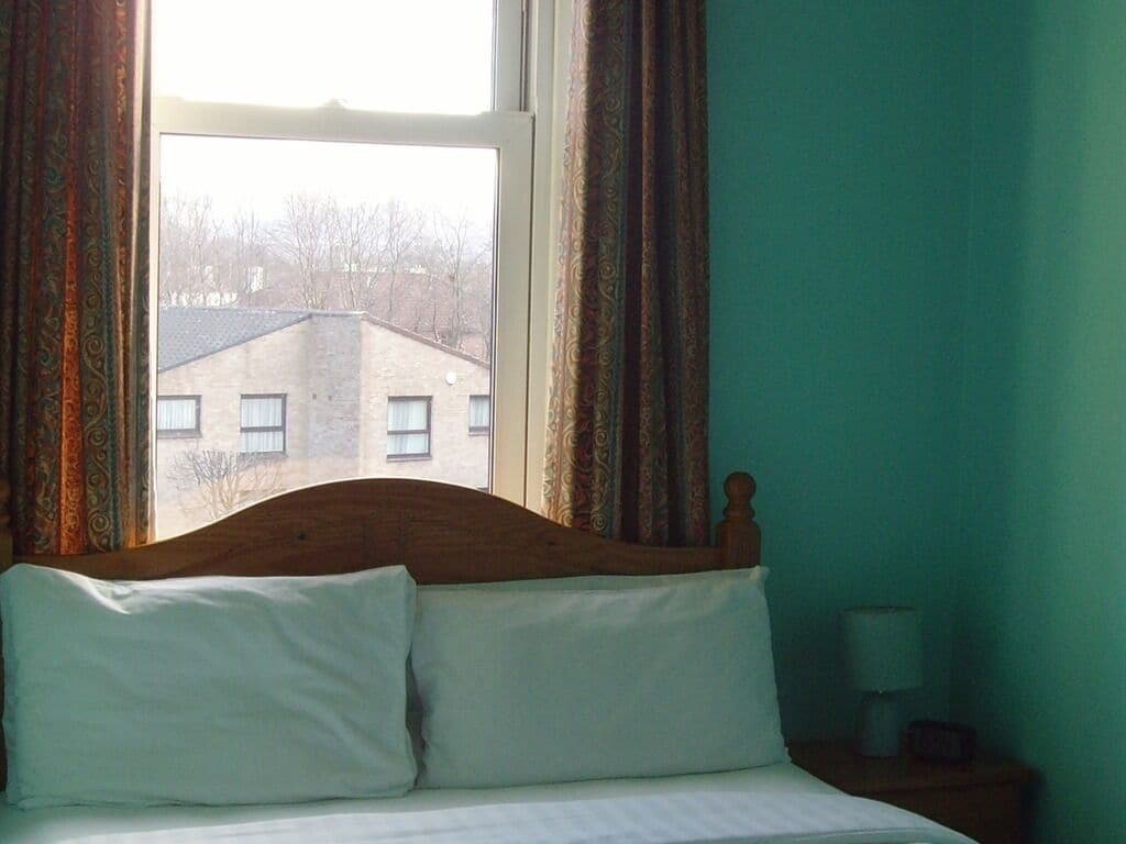 A bedroom with a bed, curtains, and a window.