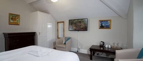 Ein Hotelzimmer mit Bett, Schreibtisch, Stuhl, Kleiderschrank und Bildern an den Wänden.