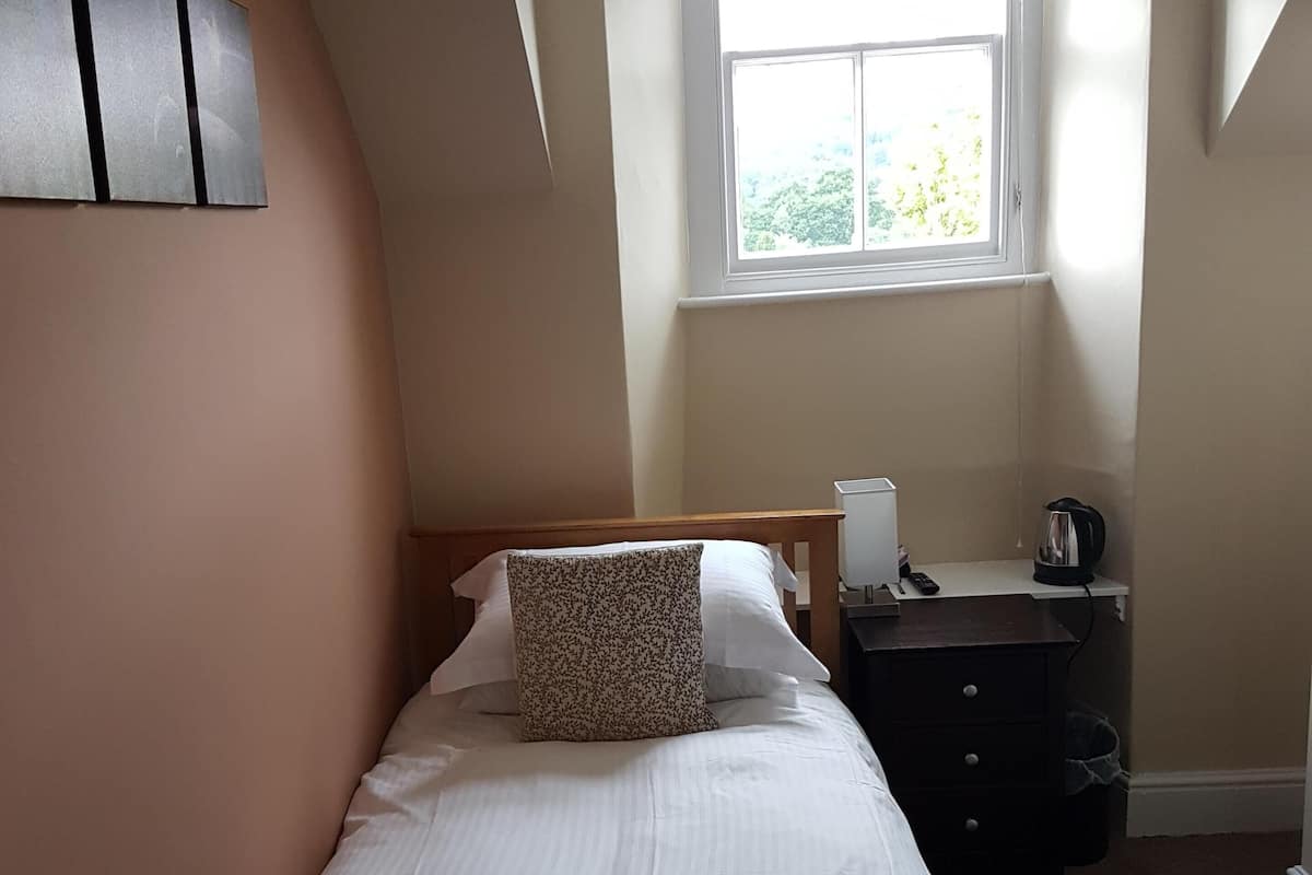 A bedroom with a bed, a dresser, a window, and a radiator.