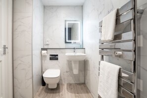 A modern bathroom with a toilet, sink, and towel rack. - Wanslea Guest House (Ambleside)