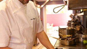 Un chef préparant des plats dans une cuisine professionnelle, équipé de divers ustensiles de cuisine et d’ingrédients.