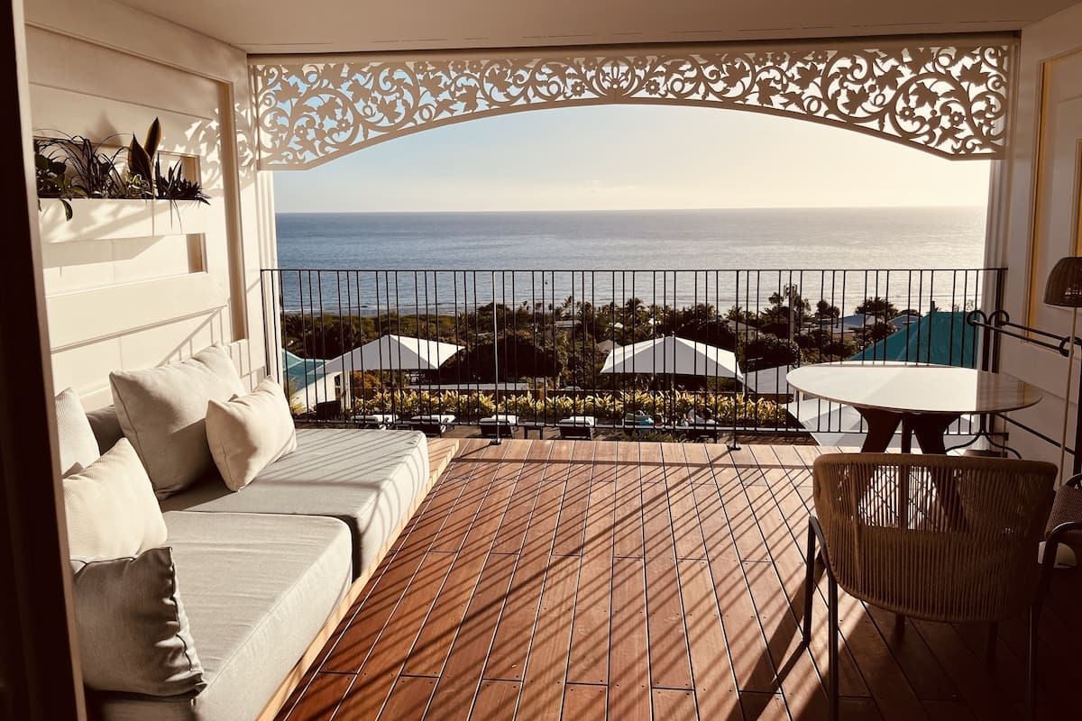 A balcony with a view of the sea, a sofa, a table, and a chair.