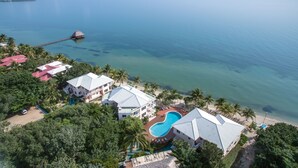 Vue aérienne d’un complexe hôtelier doté d’une piscine, d’une plage et d’une jetée s’avançant dans la mer.