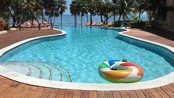 Alberca al aire libre, sombrillas en la alberca y camastros