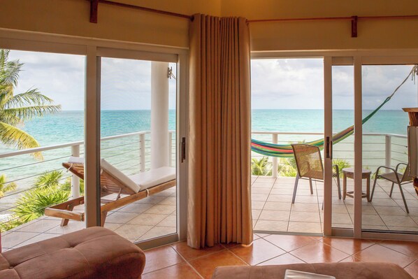 A balcony with a view of the ocean, a hammock, and lounge chairs.