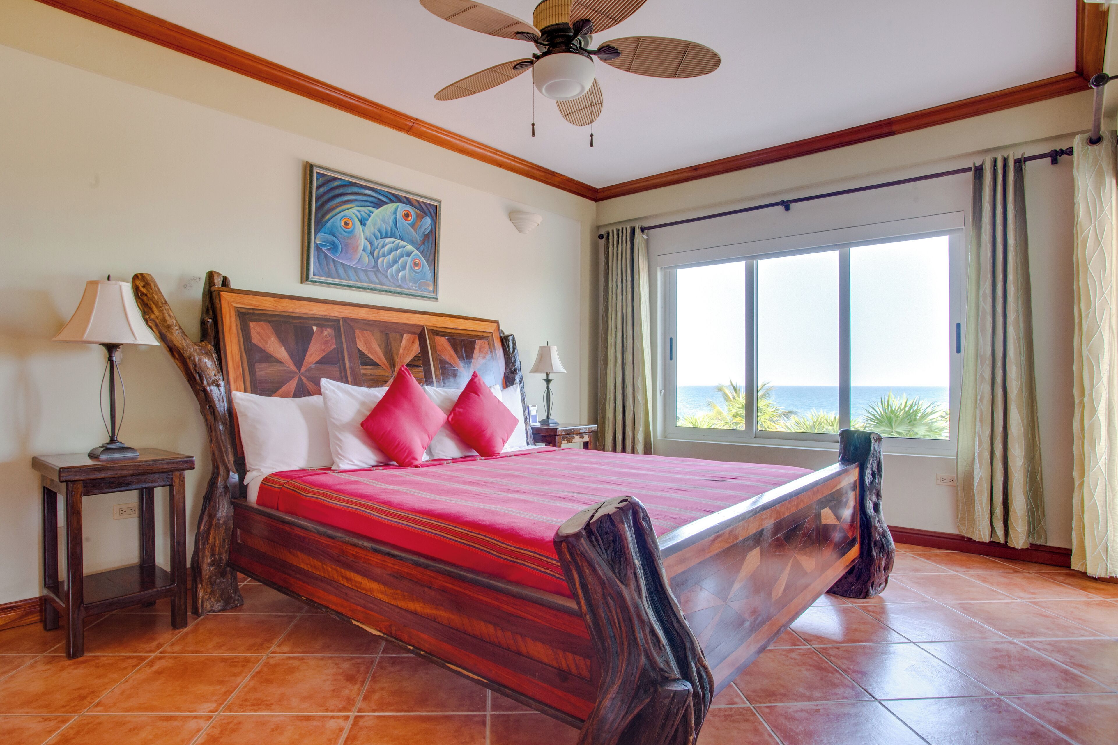 A large bed with a wooden headboard, two bedside tables, and a ceiling fan.
