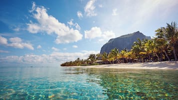 Na praia, areia branca, espreguiçadeiras, guarda-sóis