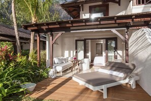 Una terraza de madera con una silla de descanso, un sofá y una mesa.