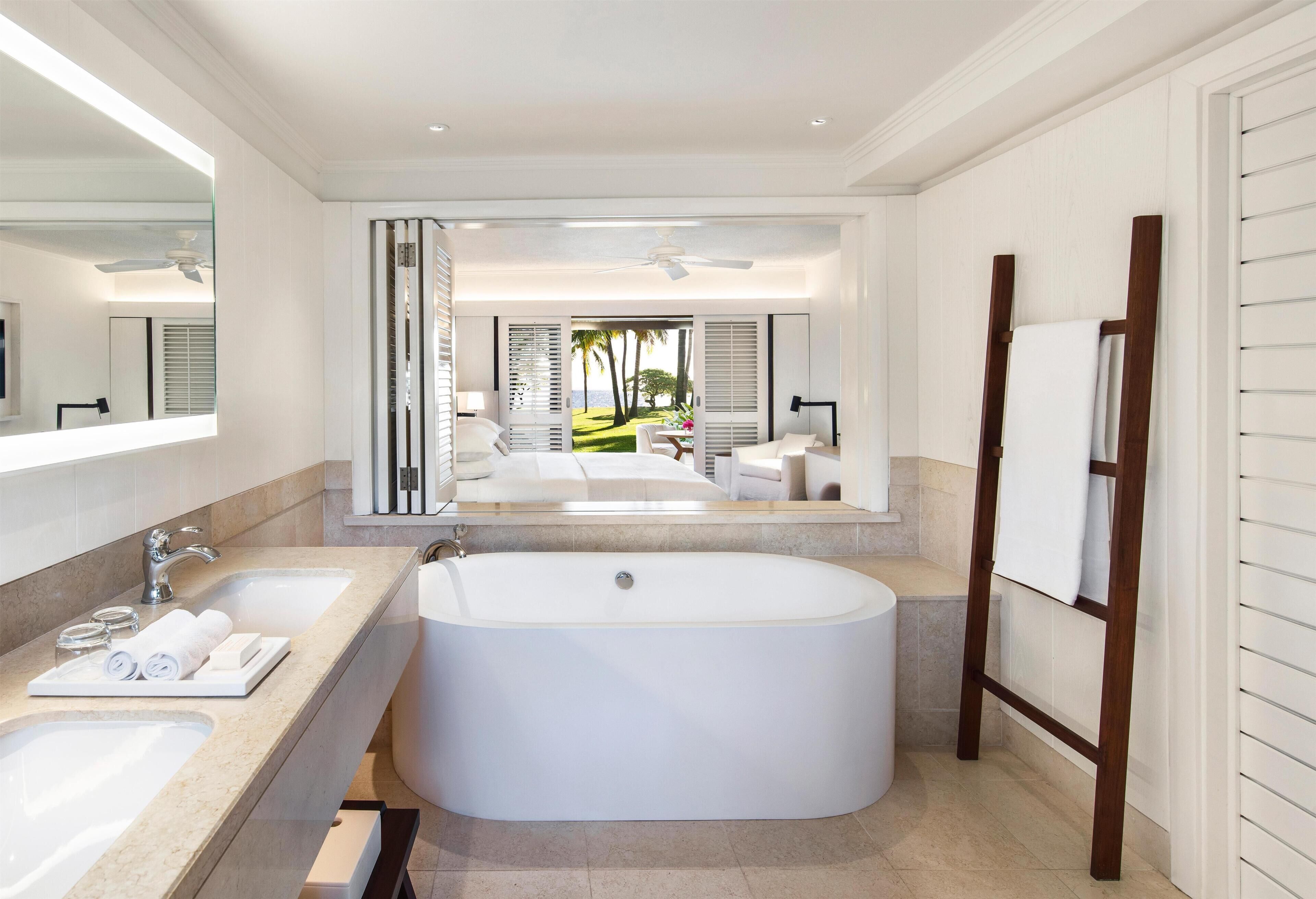 A modern bathroom with a large bathtub, two sinks, and a mirror.