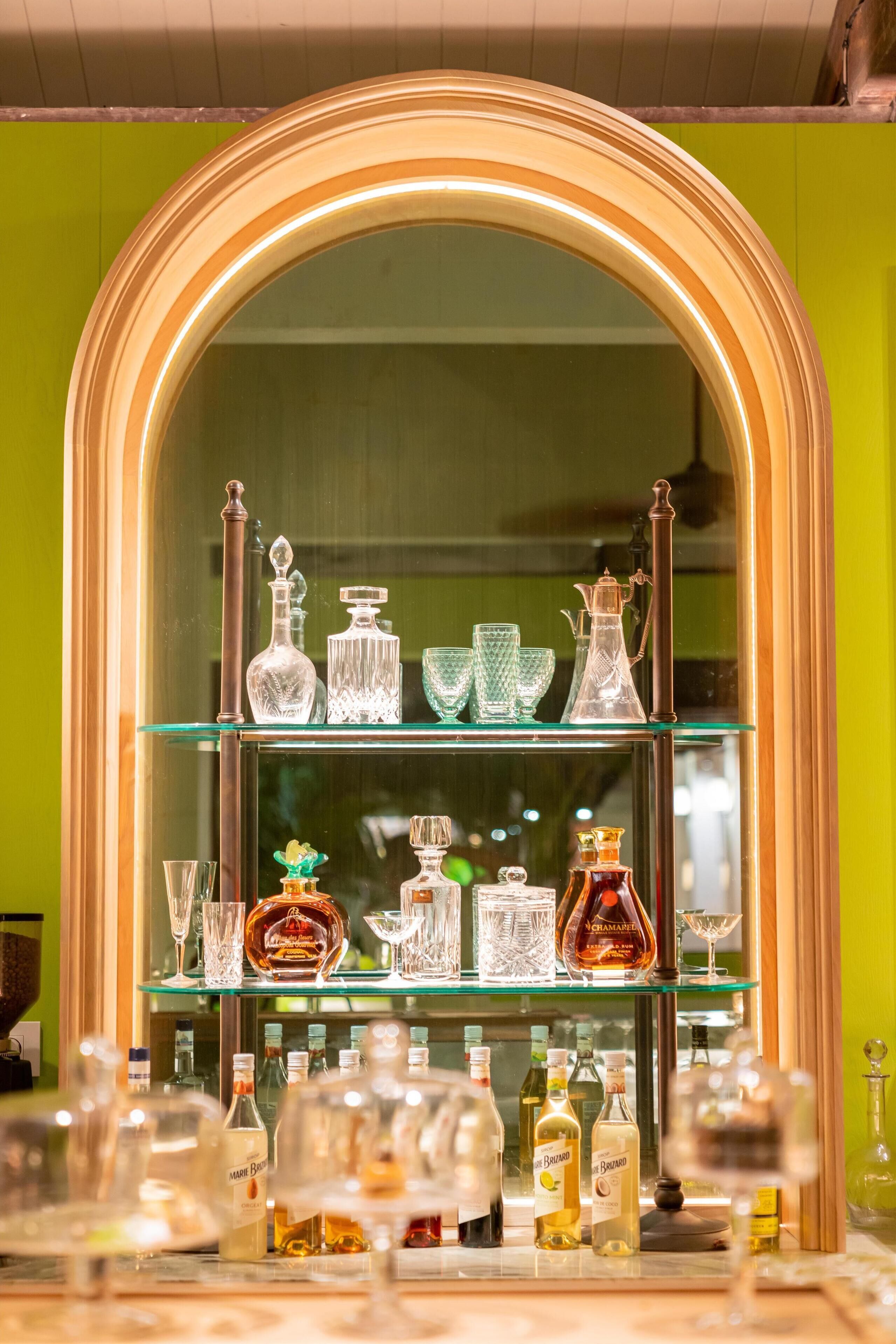 A bar area with glass shelves displaying bottles and glasses.