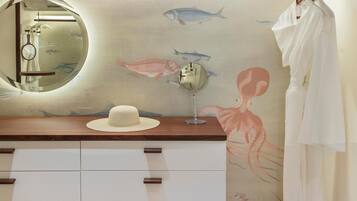 Un baño con tocador de madera, un espejo redondo y un mural en la pared con peces y un pulpo.