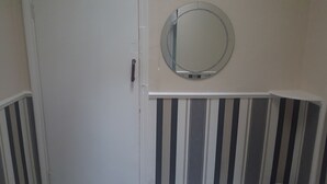 Una puerta con un espejo redondo encima, flanqueada por paneles a rayas.