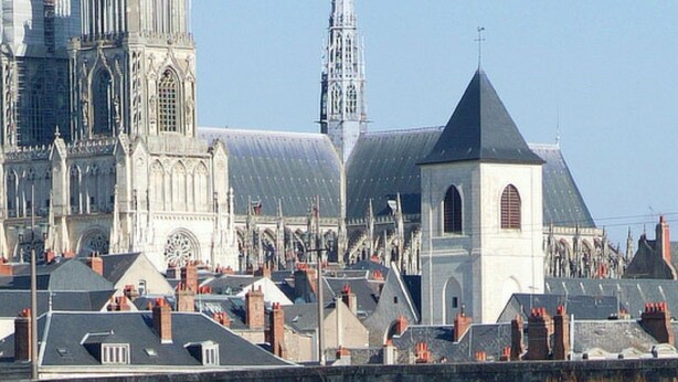 A historic cathedral with a large central spire and a smaller adjacent tower, surrounded by residential buildings with varied rooflines. - Hotel Saint Aignan (Orléans)