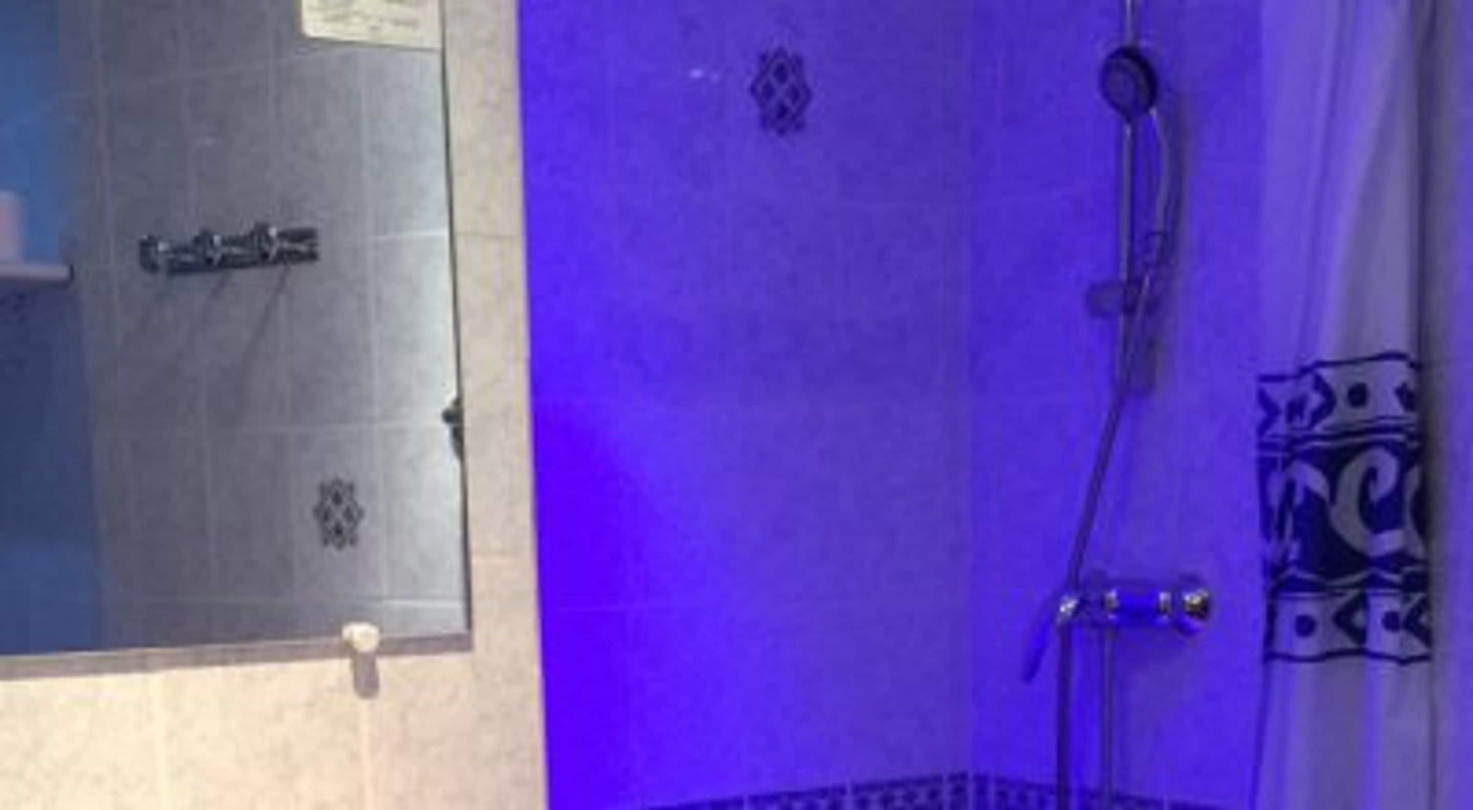 Un baño con ducha, perchero y espejo.