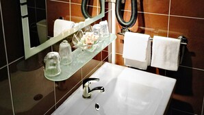 A modern bathroom with a white sink, glass soap dispenser, and a towel rack with white towels. - Hotel Saint Aignan (Orléans)