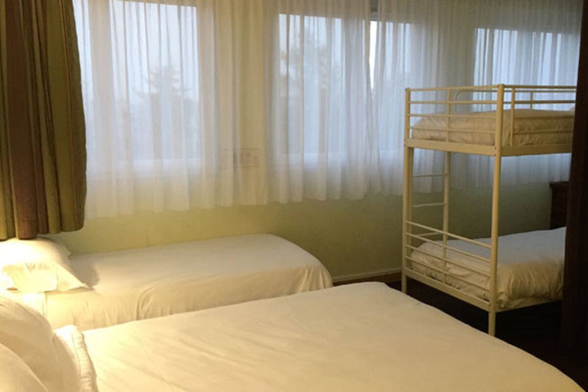 A hotel room with two single beds and a bunk bed.