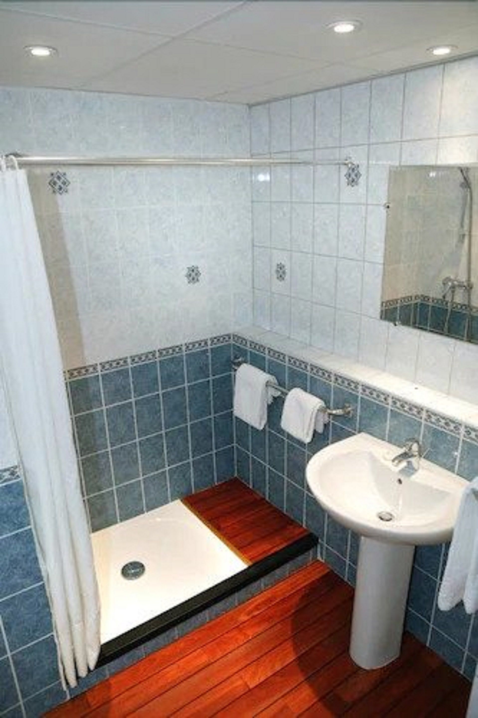Un baño con ducha, lavamanos y espejo.