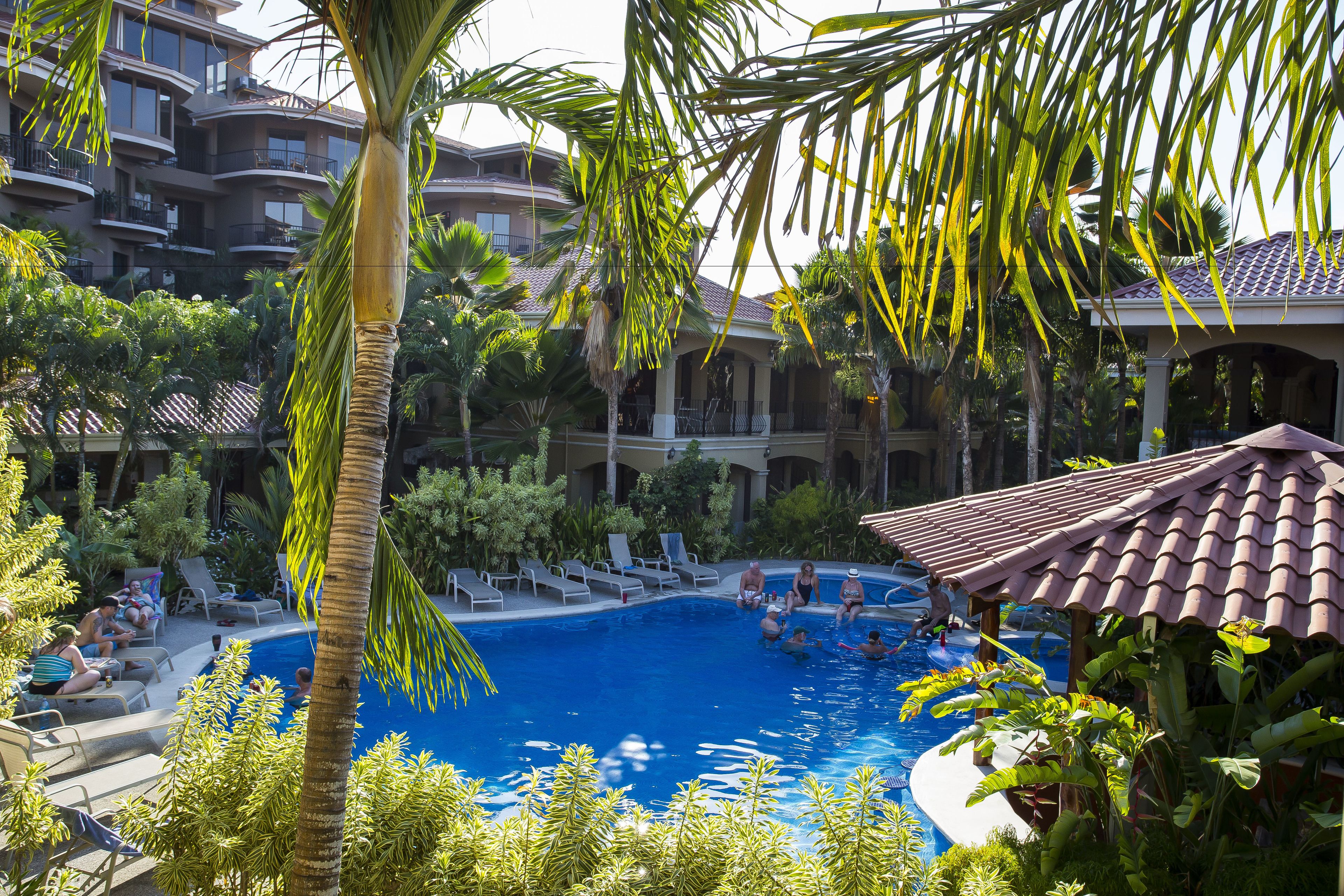 Zona de piscina con sillas de descanso y un edificio al fondo.
